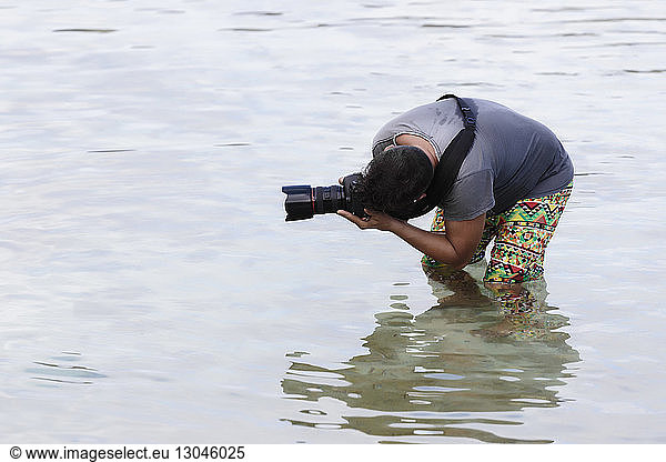 Mann fotografiert im Meer stehend