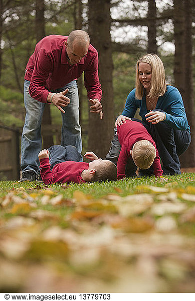 Mann gebärdet das Wort ´Play´ in amerikanischer Zeichensprache  während er mit seinem Sohn in einem Park spielt