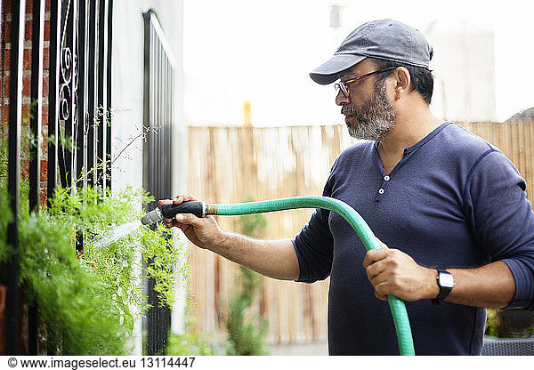 Mann gießt Pflanzen im Gartenzentrum