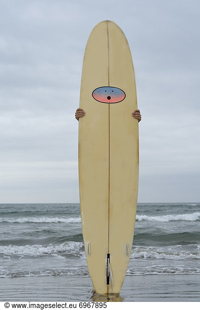 Mann  hält Surfbrett am Strand