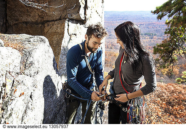 Mann hilft seiner Freundin beim Klettern