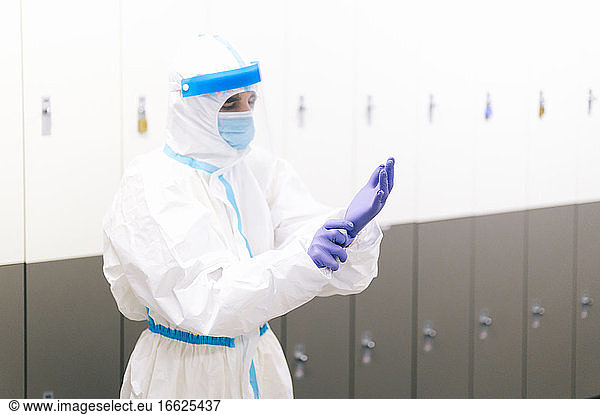 Mann im Gesundheitswesen mit Schutzanzug und Handschuhen im Krankenhaus