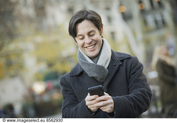 Mann im Stadtpark mit Smartphone