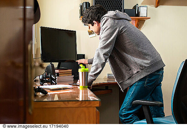 Mann im Sweatshirt schaltet den Fernseher in seinem Zimmer ein  um Videospiele zu spielen.