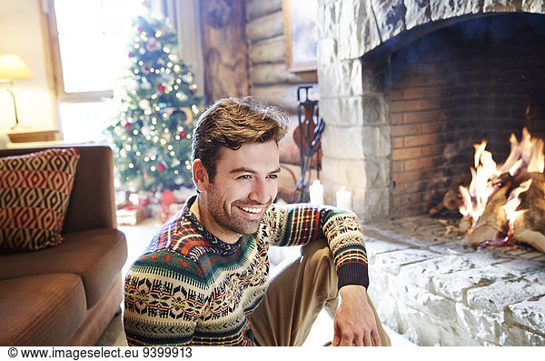 Mann im warmen Pullover genießt den Kamin