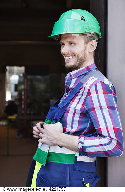 Mann in Arbeitskleidung und grünem Helm