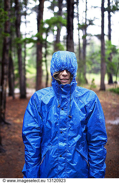 Mann in blauer Jacke im Wald stehend