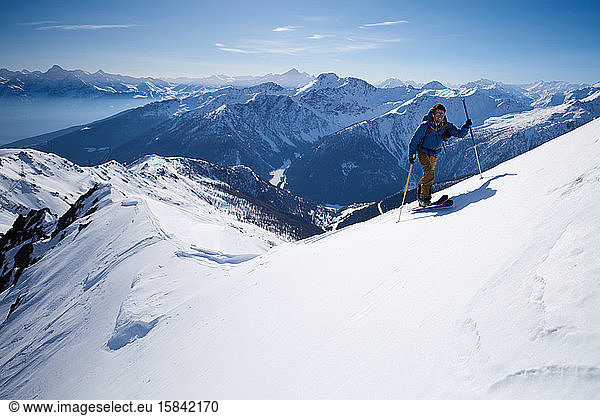 Mann in blauer Jacke Skitouren auf Bergrücken