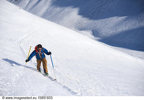 Mann in blauer Jacke Skitouren bergauf