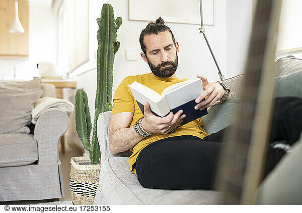 Mann in Freizeitkleidung liest zu Hause ein Buch