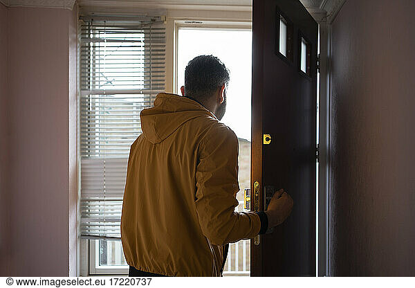 Mann in gelber Jacke öffnet Tür