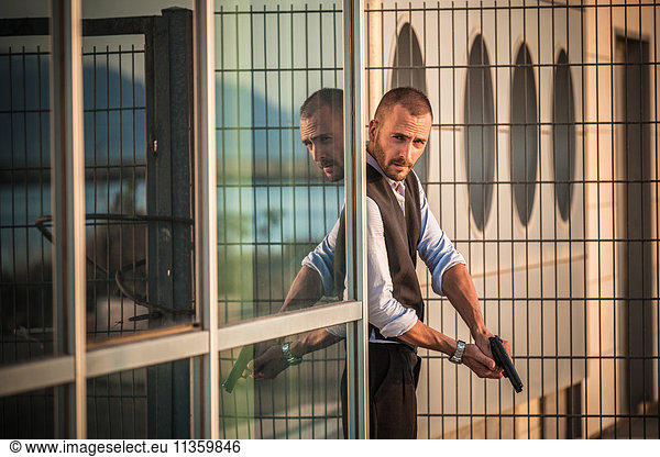 Mann in Geschäftskleidung hinter der Ecke mit Handfeuerwaffe  Cagliari  Sardinien  Italien