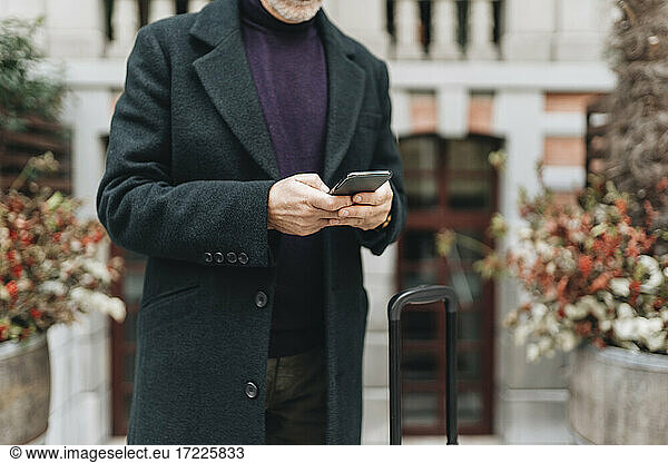 Mann in Jacke mit Mobiltelefon