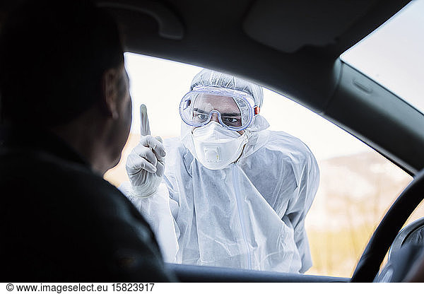 Mann in Schutzkleidung rügt älteren Mann im Auto