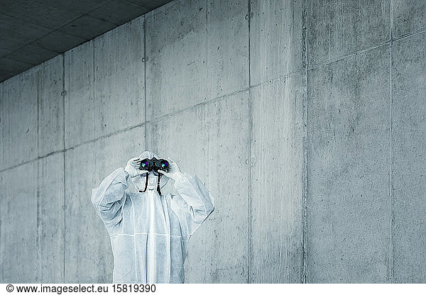Mann in Schutzkleidung schaut durch ein Fernglas