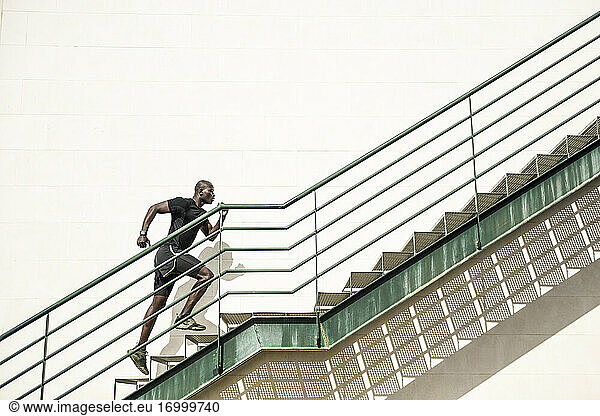 Mann in schwarzer Sportkleidung läuft eine Treppe hinauf