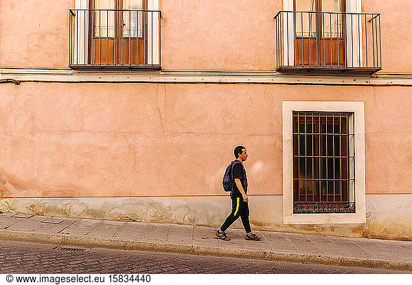 Mann in Sportkleidung geht in einer malerischen Straße in der Stadt