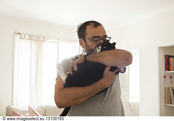 Mann küsst Katze zu Hause