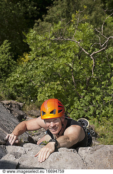 Mann klettert an steiler Felswand in Südwales