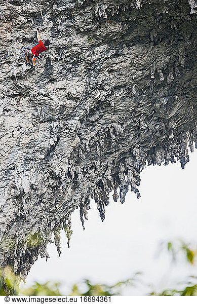 Mann klettert auf den natürlichen Felsbogen auf dem Mondberg in Yangshuo