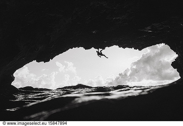 Mann klettert in einer vulkanischen Höhle über den Ozean