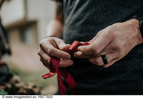 Mann knüpft Knoten in rote Sicherheitsgurte