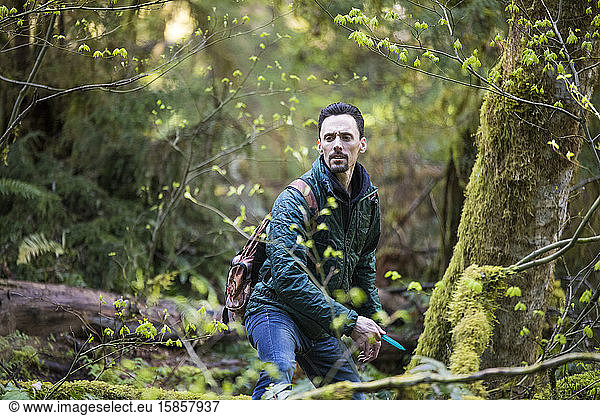 Mann konzentriert sich beim Scheibengolfspiel im Wald auf das Ziel.