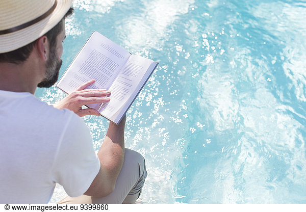 Mann liest Buch über Schwimmbad