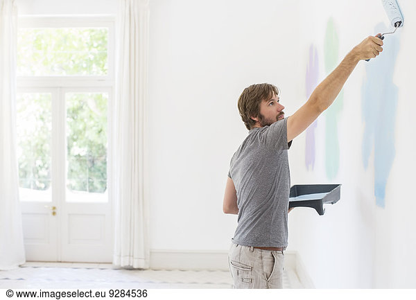 Mann malt Wand im Wohnraum