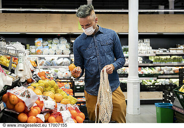Mann mit Gesichtsmaske kauft Obst im Supermarkt