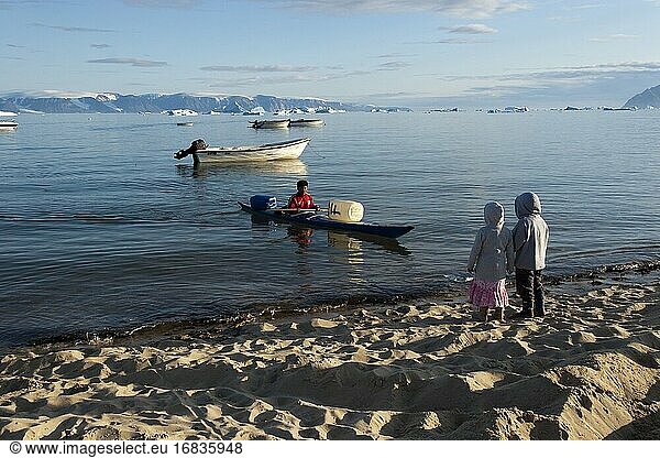 Mann mit Kajak und Kindern am Strand in Qaanaaq  Grönland.