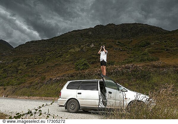 Mann mit Kamera auf dem Autodach  Queenstown  Region Otago  Queenstown-Lakes District  Südinsel  Neuseeland  Ozeanien