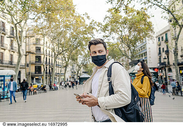 Mann mit Maske findet Adresse auf Telefon in Las Ramblas
