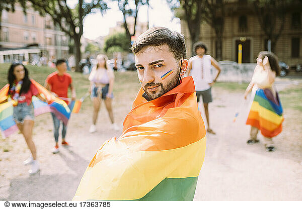 Mann mit Regenbogenfahne bei Pride-Veranstaltung eingewickelt