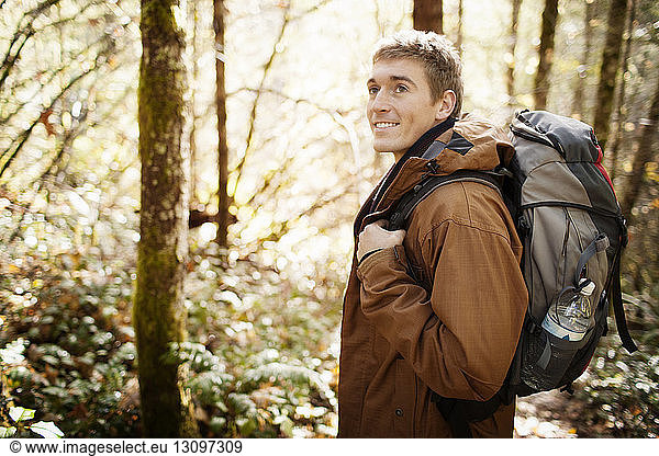 Mann mit Rucksack beim Wegschauen im Wald