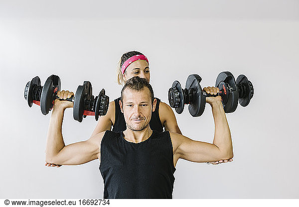 Mann mit seinem Personal Trainer beim Training im Fitnessstudio