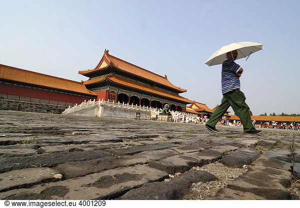 Mann mit Sonnenschirm läuft über Steinpflaster  Verbotene Stadt  Kaiserpalast  Peking  China  Asien
