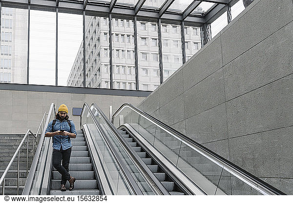 Mann mit stehendem Mann auf Rolltreppe mit Smartphone  Berlin  Deutschland