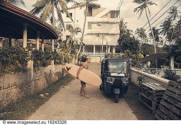 Mann mit Surfbrett neben Tuk Tuk