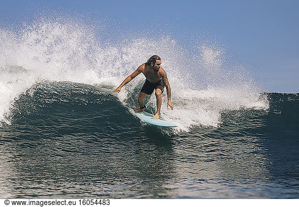 Mann ohne Hemd surft auf dem Meer gegen den klaren Himmel  Bali  Indonesien