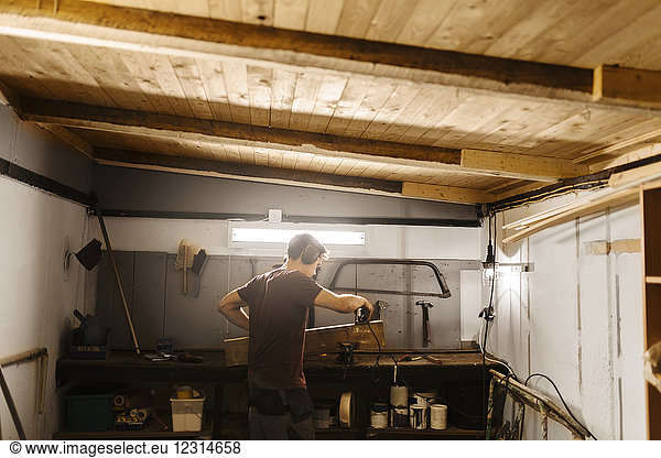 Mann poliert Holz in der Garage