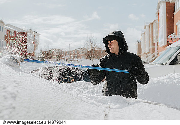 Mann räumt schneebedecktes Fahrzeug mit Besen  Toronto  Kanada