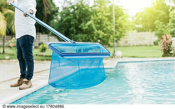 Mann reinigt den Pool mit dem Skimmer  Ein Mann reinigt Pool mit Blatt Skimmer. Person mit Skimmer Reinigung Pool  Hände halten einen Skimmer mit blauen Pool im Hintergrund
