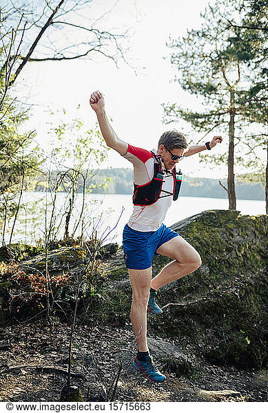 Mann rennt am Seeufer und springt über ein Hindernis  Forstsee  Kärnten  Österreich