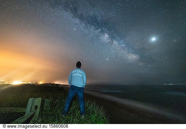 Mann schaut auf die Milchstraßen-Galaxie über dem Strand von Nantucket.
