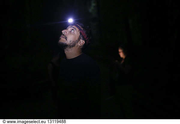 Mann schaut nachts mit Scheinwerfer auf