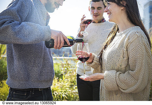 Mann schenkt während Gartenparty Rotwein für Freundin ein