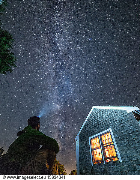 Mann sitzt an Deck und schaut auf die Milchstraßen-Galaxie auf Nantucket.