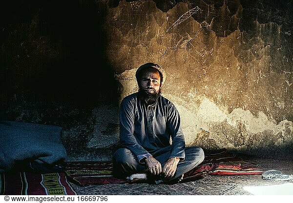 Mann sitzt auf einem Teppich  traditionelles Lehmhaus  Khas Dej  Wakhan-Korridor  Afghanistan  Asien