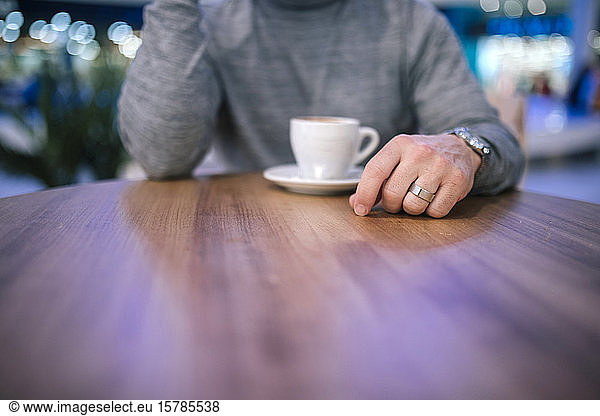 Mann sitzt in Cafeteria  trinkt Kaffee  Nahaufnahme